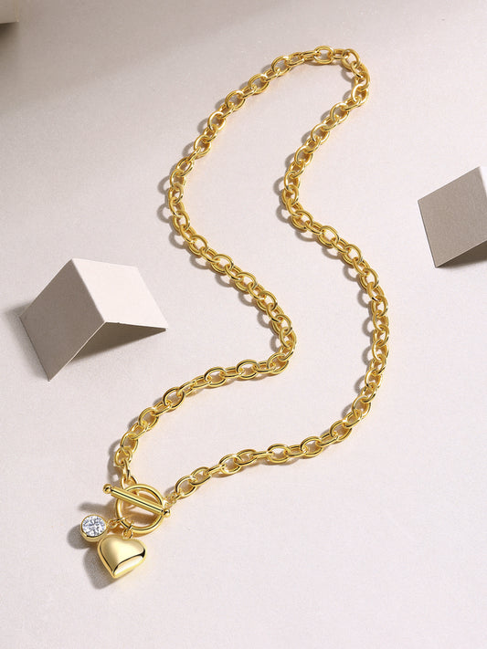 Gold necklace with a heart-shaped pendant on a light gray background