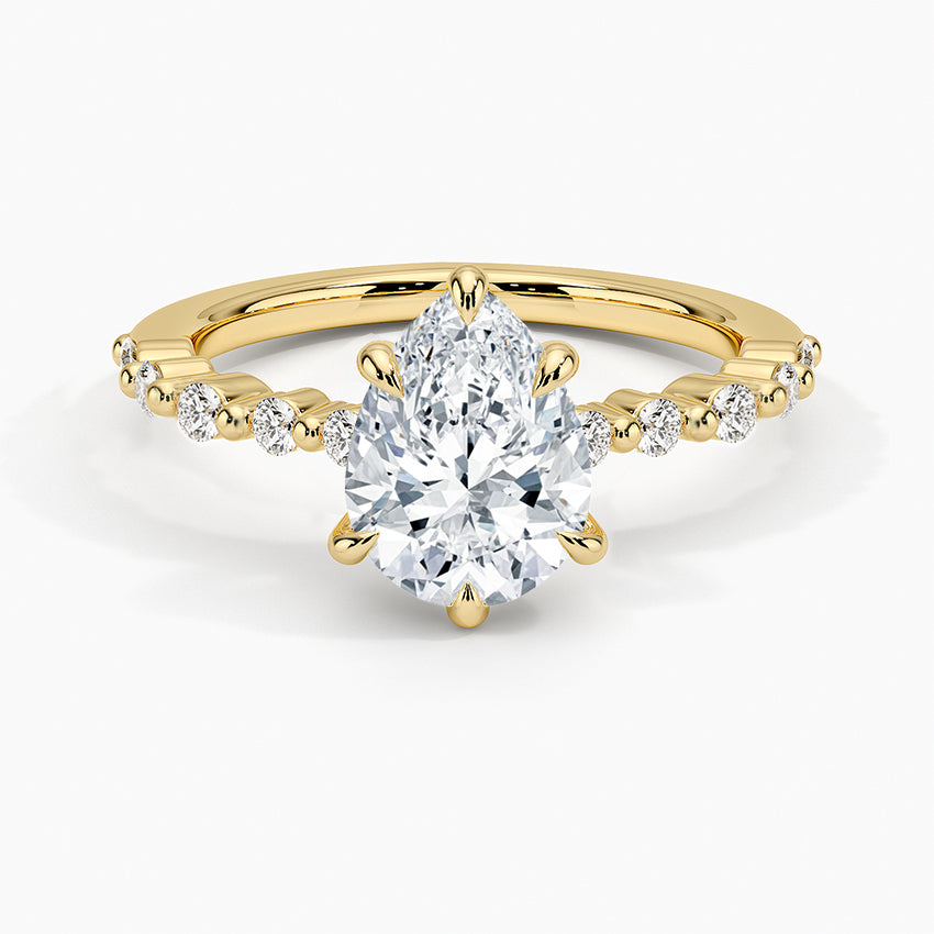 Gold ring with a large diamond and smaller diamonds on the band against a white background. Pear Cut Accent Band Moissanite Ring