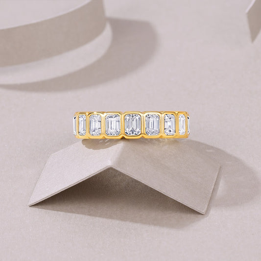 Gold ring with emerald-cut diamonds on a beige background