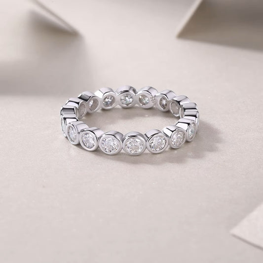 Silver ring with round diamonds on a light gray background
