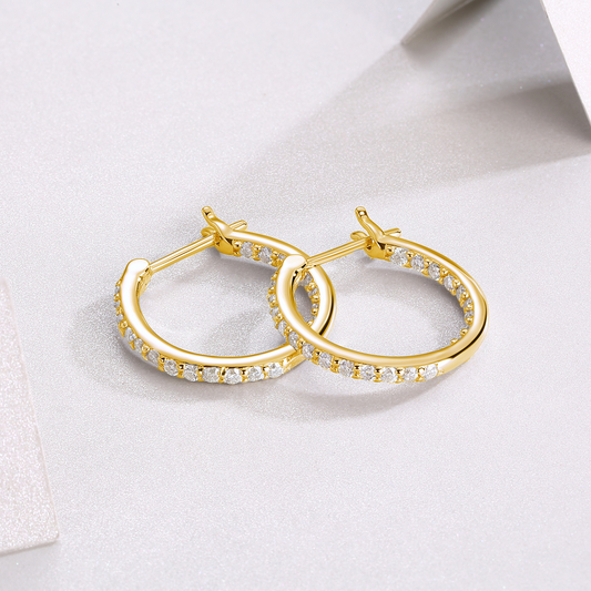 Gold hoop earrings with embedded diamonds on a light background