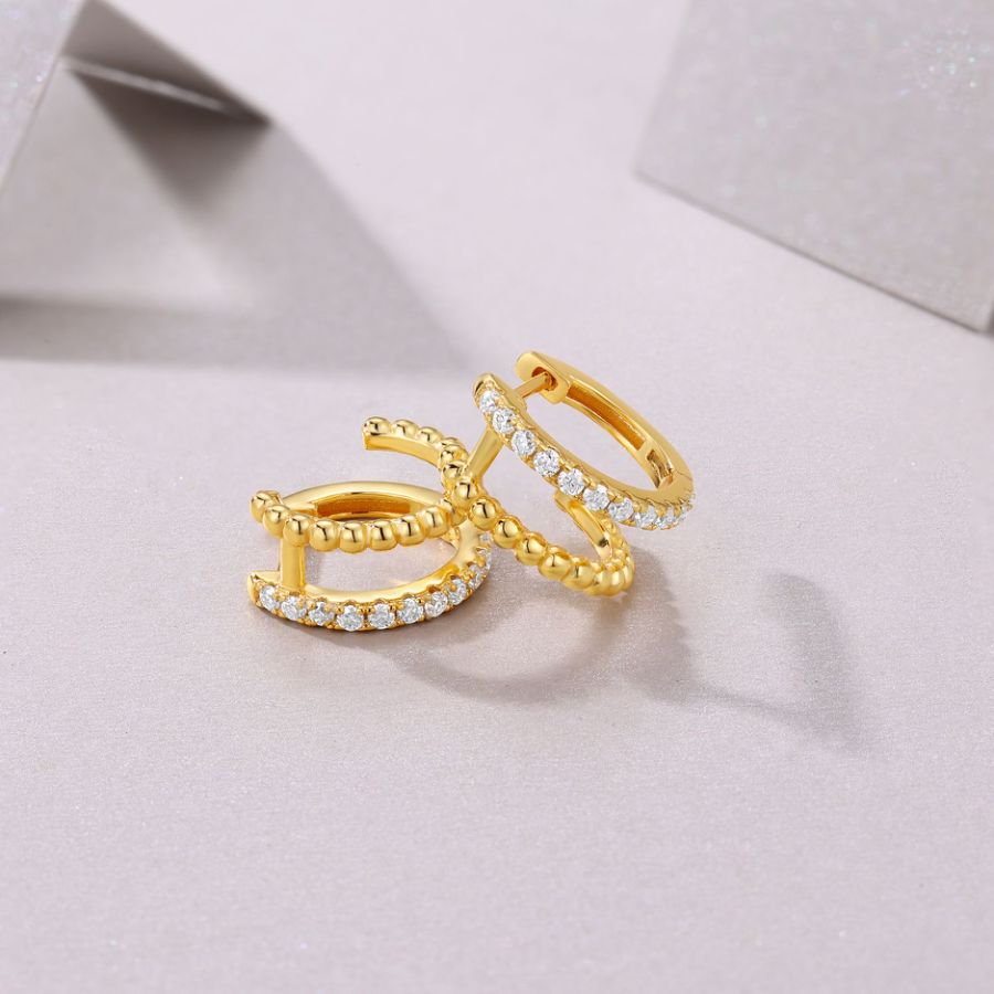 Gold rings with diamond accents on a light gray fabric background