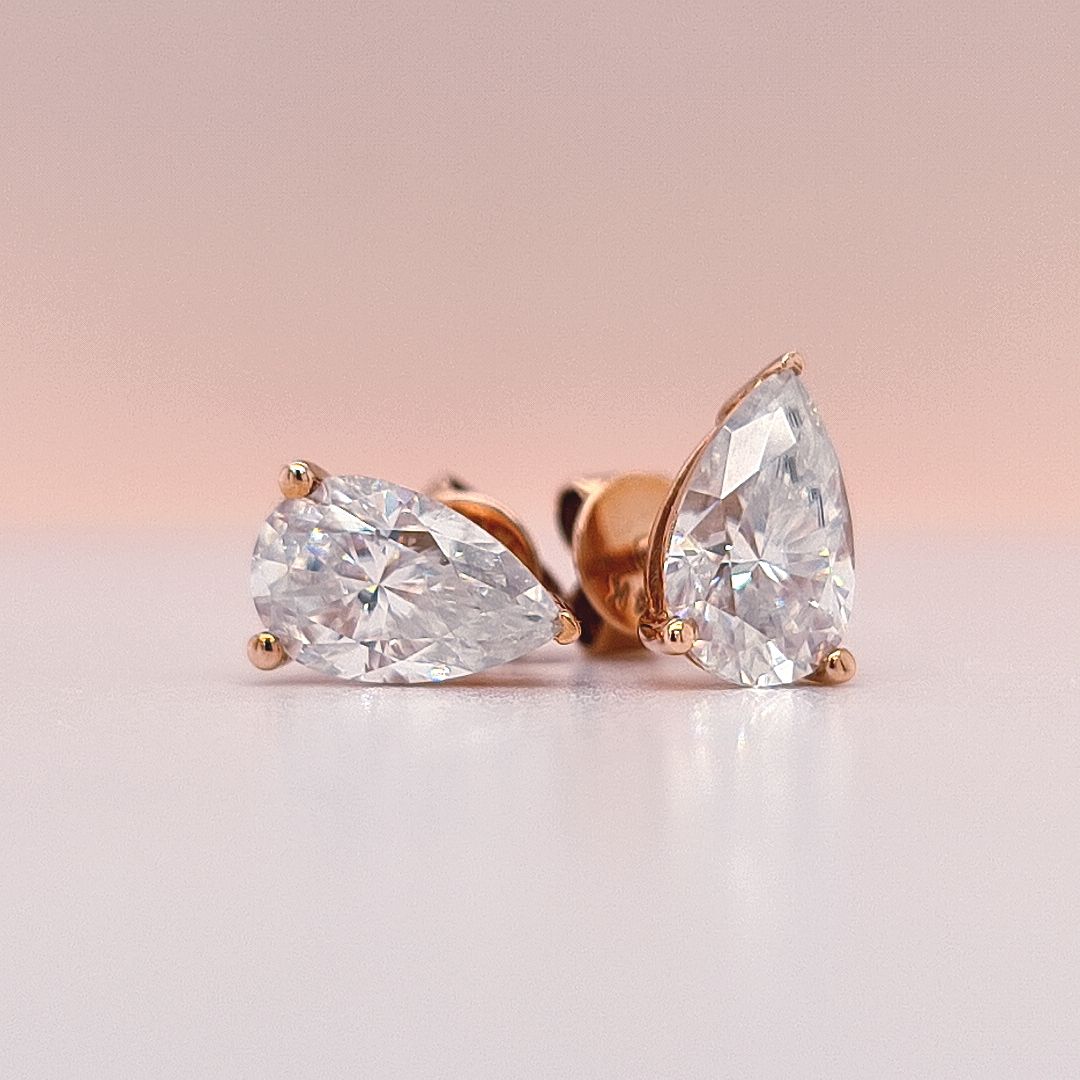 Gold earrings with pear-shaped moissanite diamonds in 14K gold on a white background