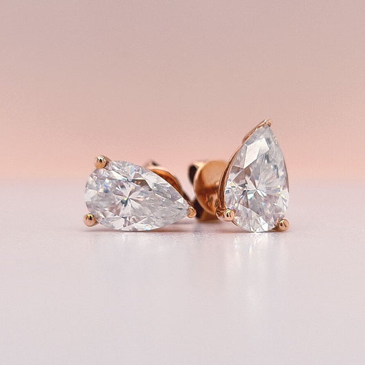 Gold earrings with pear-shaped moissanite diamonds in 14K gold on a white background