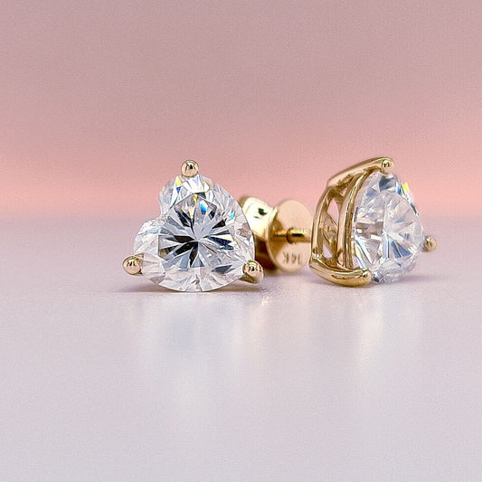 Heart-shaped moissanite diamond earrings with gold prongs on a white background 14K gold