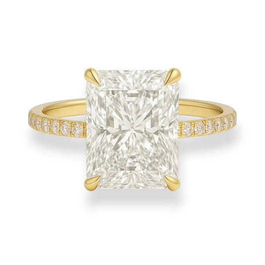 Gold ring with a large diamond and smaller diamonds on the band against a white background.  5.2ct radiant cut moissanite solitaire engagement ring with pavé band in yellow gold – Gems of Elah