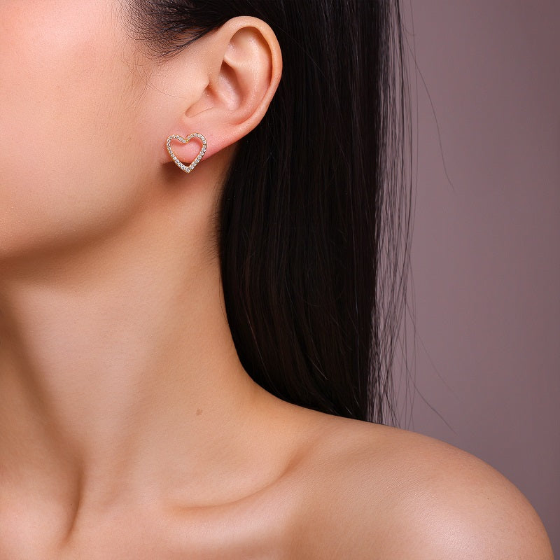 Heart-shaped earring worn by a person with a neutral background