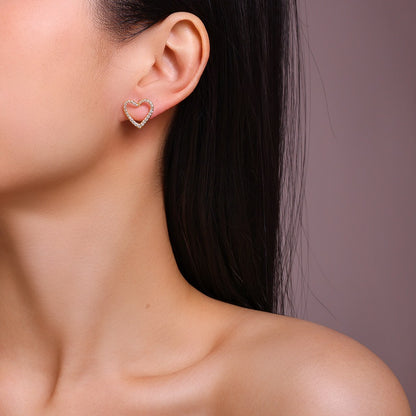 Heart-shaped earring worn by a person with a neutral background