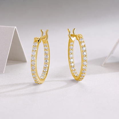 Gold hoop earrings with clear stones on a light gray background