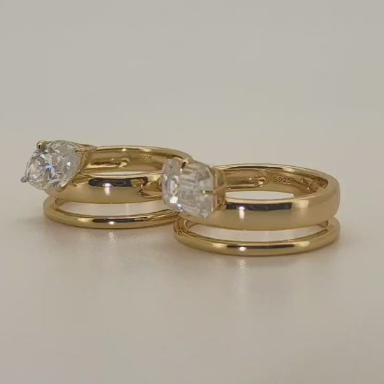 Two gold-plated sterling silver moissanite 2 carat rings displayed side by side on a soft neutral background—one with a marquise-cut stone set east-west, the other with an emerald-cut moissanite. Both styles feature matching plain gold bands beneath the main ring.